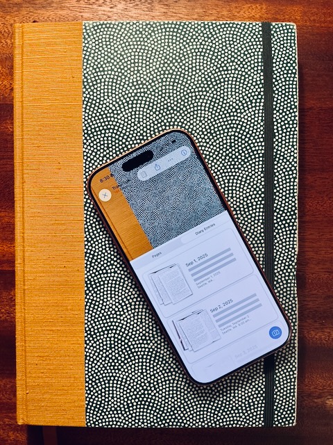 A photo of a diary with a phone on top containing a digital copy of the same diary.